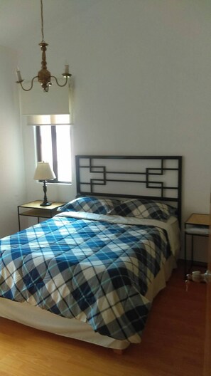 A bedroom with a bed, a nightstand, a lamp, and a window. - Departamento Comodo, Centrico, Estacionamiento (Querétaro)