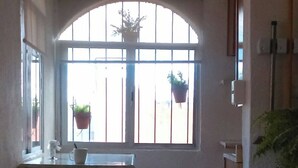 A narrow hallway with a window, a small table with a chair, and a potted plant. - Departamento Comodo, Centrico, Estacionamiento (Querétaro)