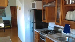 A kitchen with wooden cabinets, a stainless steel refrigerator, a microwave, a stove, and a sink. - Departamento Comodo, Centrico, Estacionamiento (Querétaro)
