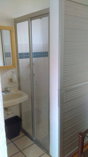 A bathroom with a glass shower door, a sink, and a tiled floor. - Departamento Comodo, Centrico, Estacionamiento (Querétaro)