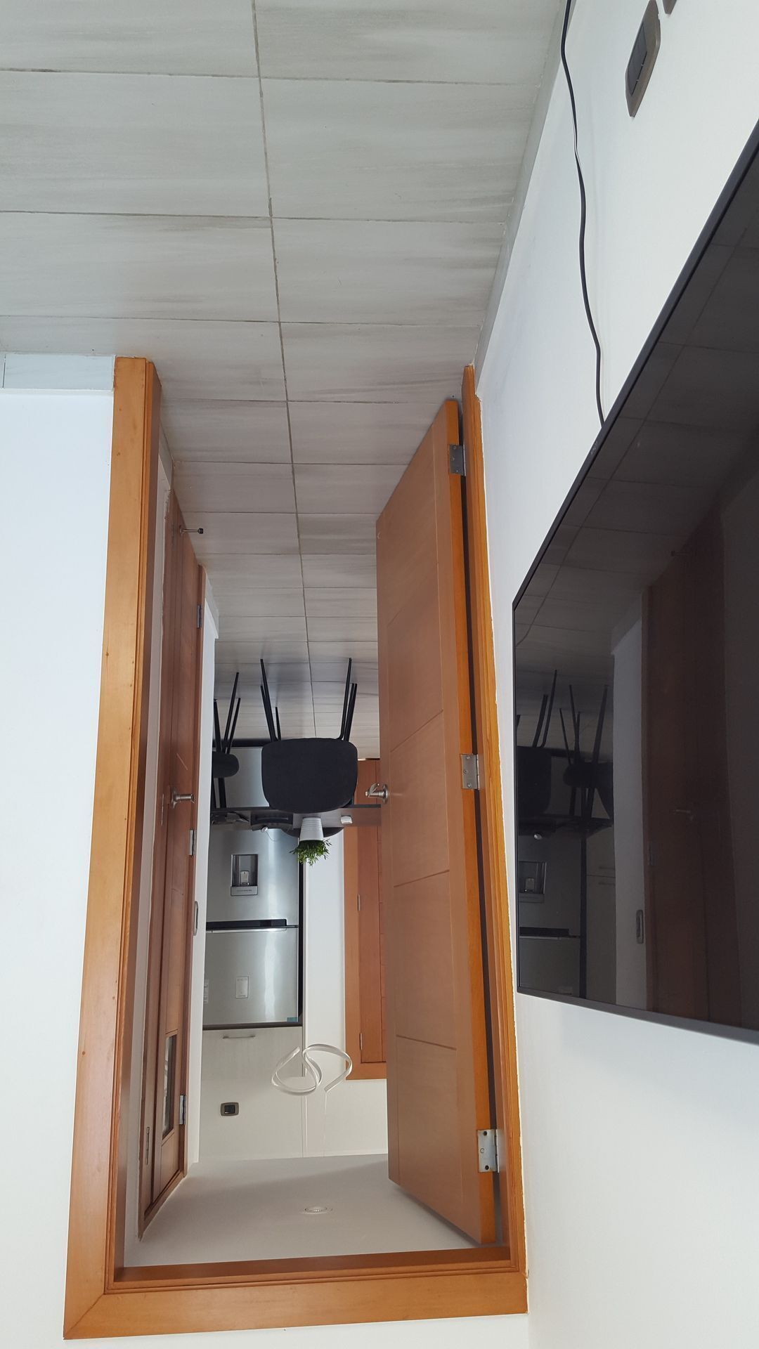 A narrow hallway with wooden doors leading to a kitchen area.