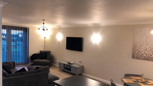 A living room with a sofa, a TV, a dining table with chairs, and a kitchen area with a countertop. - 2 Bedroom & 2 Bathroom Riverside Apartment Little Paxton St Neots (St Neots)