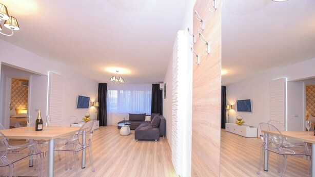 Uma sala de estar moderna com um sofá, uma mesa de jantar com cadeiras e um lustre.