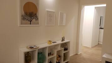 A hallway with a white console table displaying various decorative items, a framed artwork above it, and a door leading to another room.