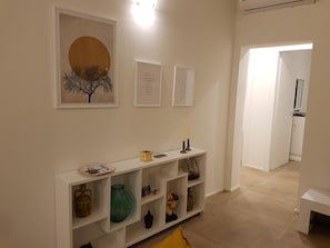 A hallway with a white console table displaying various decorative items, a framed artwork above it, and a door leading to another room.