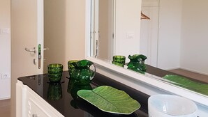 Ein Badezimmer mit schwarzem Waschtisch, einer grünen, blattförmigen Seifenschale, einem grünen Krug und einer weißen Schüssel.