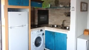 Una cocina compacta con lavadora, microondas y lavamanos.