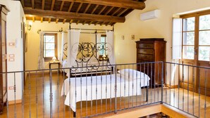 A bedroom with a wooden ceiling, a bed with a metal frame, a wooden dresser, and a window with curtains. - Podere Caldaruccio La Pineta - Cottage Umbertide (Perugia)