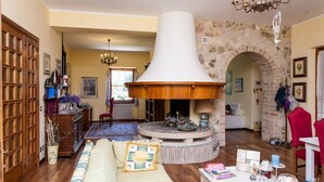 A cozy living room with a fireplace, wooden furniture, and a stone wall. - Podere Caldaruccio La Pineta - Cottage Umbertide (Perugia)