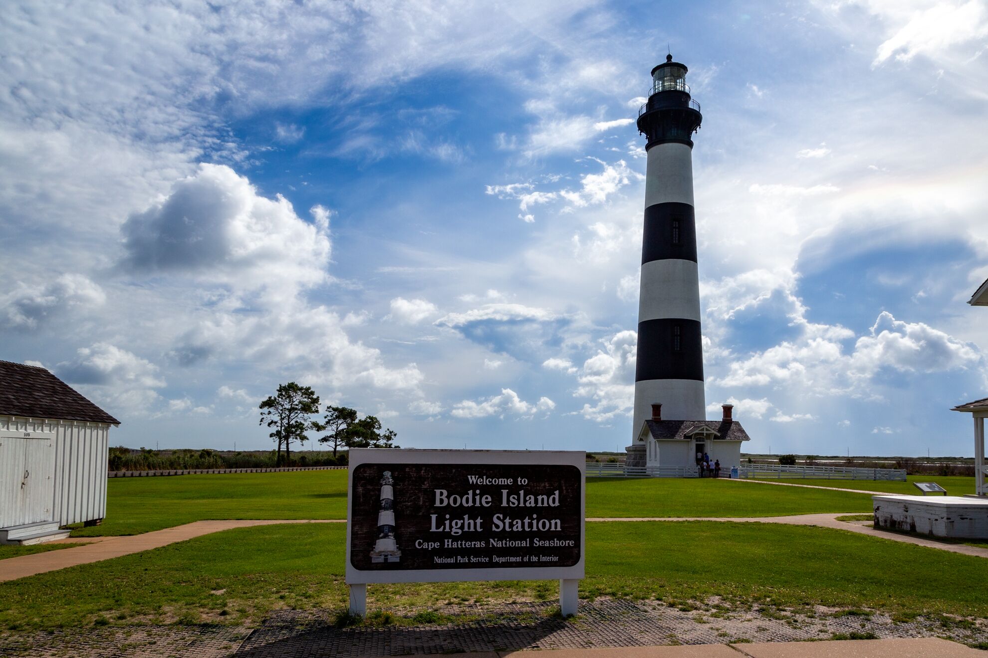 A lighthouse with a sign in front.