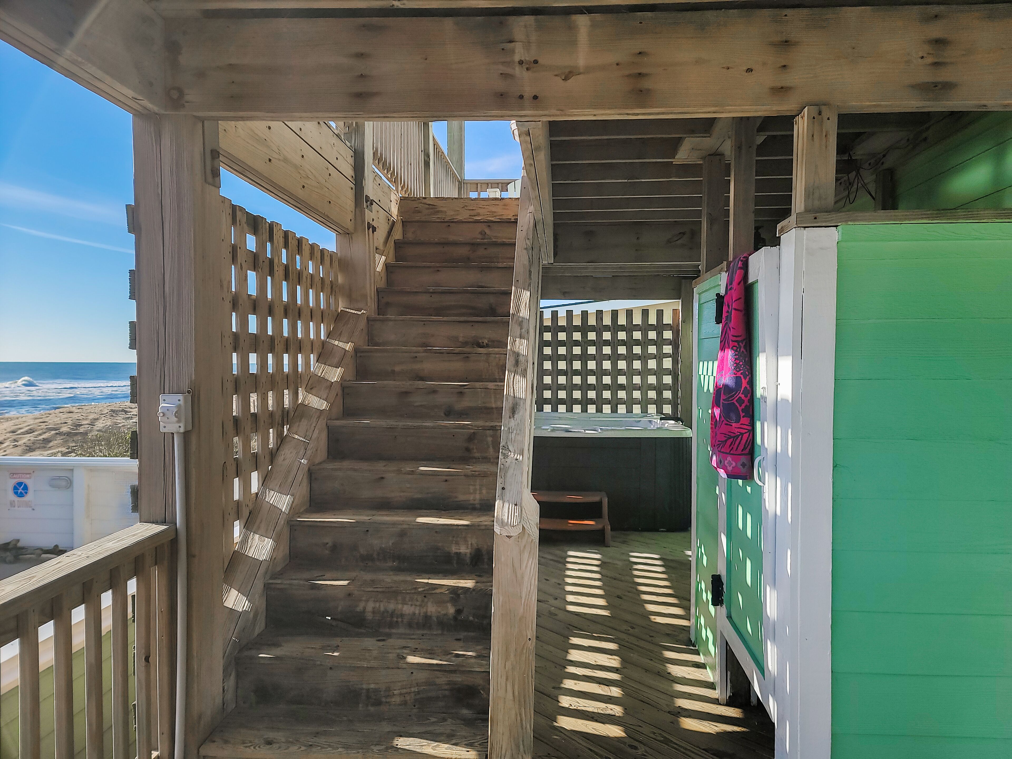 A wooden staircase leading to a deck with a view of the beach.