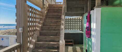 A wooden staircase leading to a deck with a view of the beach.