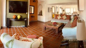 A living room with a TV, sofa, and coffee table. - Sunny Apartment In The Heart of the Exclusive Marina Vallarta (Puerto Vallarta)