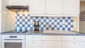 A kitchen with white cabinets, a checkered backsplash, a coffee maker, and a built-in oven. - Résidence Ker Eden by Interhome (Quiberon)