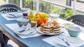 A breakfast setup on a balcony with a table, chairs, and a fruit basket. - Résidence Ker Eden by Interhome (Quiberon)
