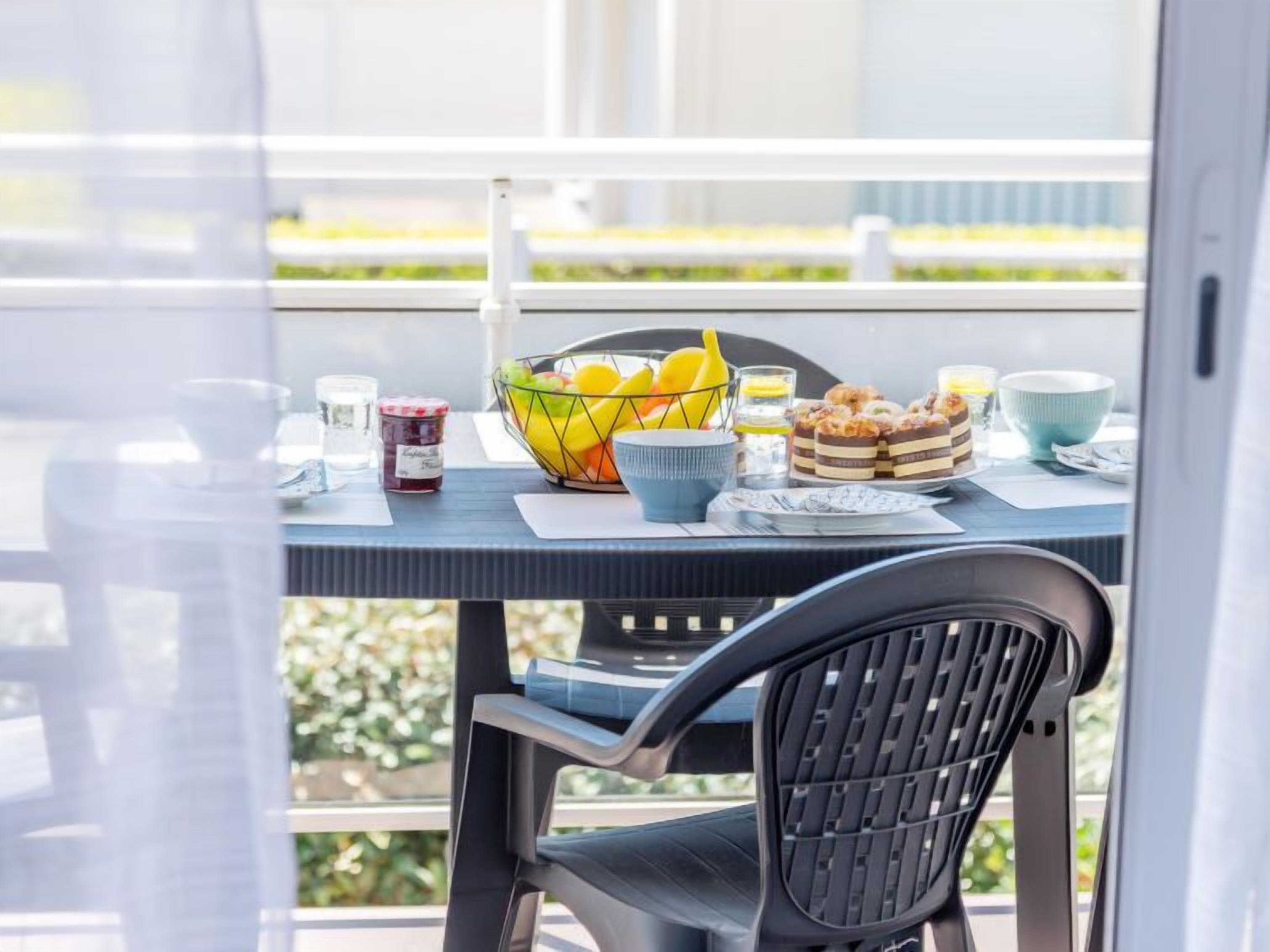 A dining table with a fruit bowl, a candle, and a plate of pastries.