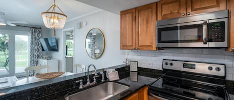 A modern kitchen with wooden cabinets, a stainless steel sink, a microwave, and an oven.