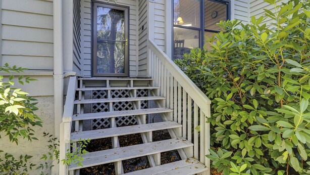Un escalier en bois mène à une porte d’entrée surmontée d’une décoration en forme de roue de navire.