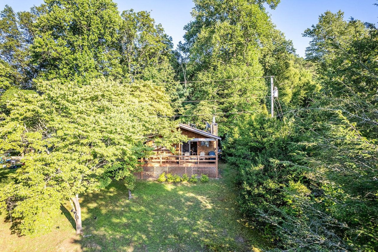 A cabin surrounded by dense forest, with a deck and outdoor seating area.