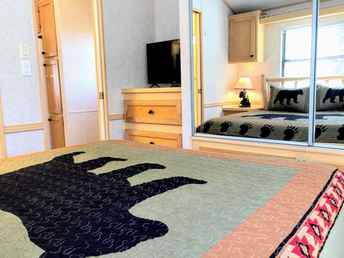 A bedroom with a large bed, a dresser, a television, and a window with a view.