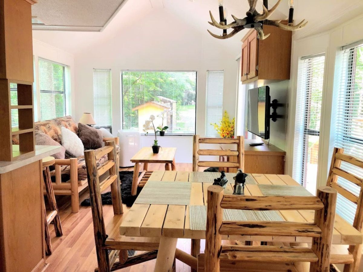 A cozy, rustic interior with wooden furniture, a dining table, and a kitchen area with a refrigerator and cabinets.