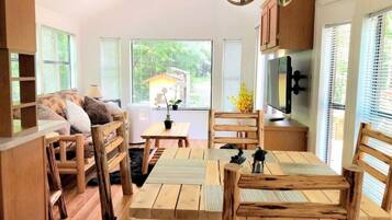 A cozy, rustic interior with wooden furniture, a dining table, and a kitchen area with a refrigerator and cabinets.