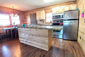Eine Küche mit Holzausstattung, einem Edelstahlkühlschrank, einer Mikrowelle und einem Backofen.
