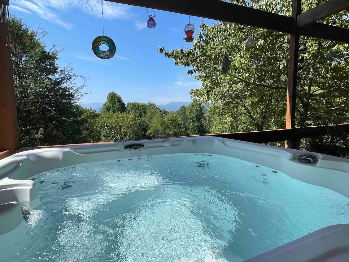 Un jacuzzi con vistas despejadas a los árboles y montañas circundantes.