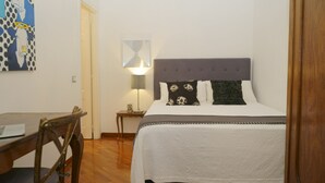 A bedroom with a bed, a bedside table, a lamp, a chair, and a painting on the wall. - 2 Bedroom Trastevere (Rome)