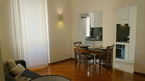 A living room with a sofa, a dining table with chairs, and a kitchen area with cabinets and appliances. - 2 Bedroom Trastevere (Rome)