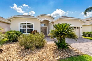 A residential building with a driveway, a large window, and a palm tree.