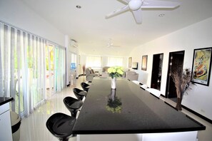 Un espace repas moderne avec une longue table, des chaises noires et un vase rempli de fleurs.