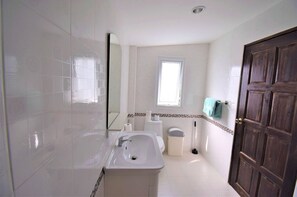 Une salle de bain avec une baignoire, un lavabo, des toilettes et une fenêtre.