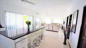 Ett modernt kök med en central köksö, barstolar och en matplats med en soffa.