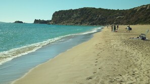 A beach with clear blue water, sandy shore, and rocky cliffs in the background. - Despite Corona Summer Vacation on Southern Greek Beaches (Pylos-Nestoras)