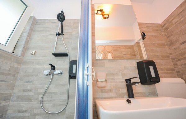 Un baño moderno con ducha, inodoro y lavamanos.