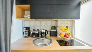 A modern kitchen with a built-in sink, a coffee maker, a toaster, and a fruit basket. - One by One - Adam's Studio - Cismigiu Gardens (Bucharest)