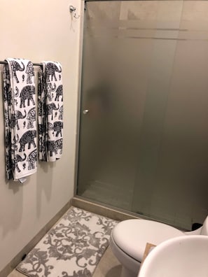 A bathroom with a shower, toilet, and patterned towels. - Beautiful Condo 300 Meters To Medano Beach (Cabo San Lucas)