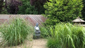 A garden with a Buddha statue surrounded by tall grasses and a wooden fence. - Holiday Home 'Haus Piratennest' with Private Terrace, Garden & Wi-Fi (Grömitz)