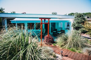 Een modern gebouw met een blauwe buitenkant, een rode ingang en een patio met planten.