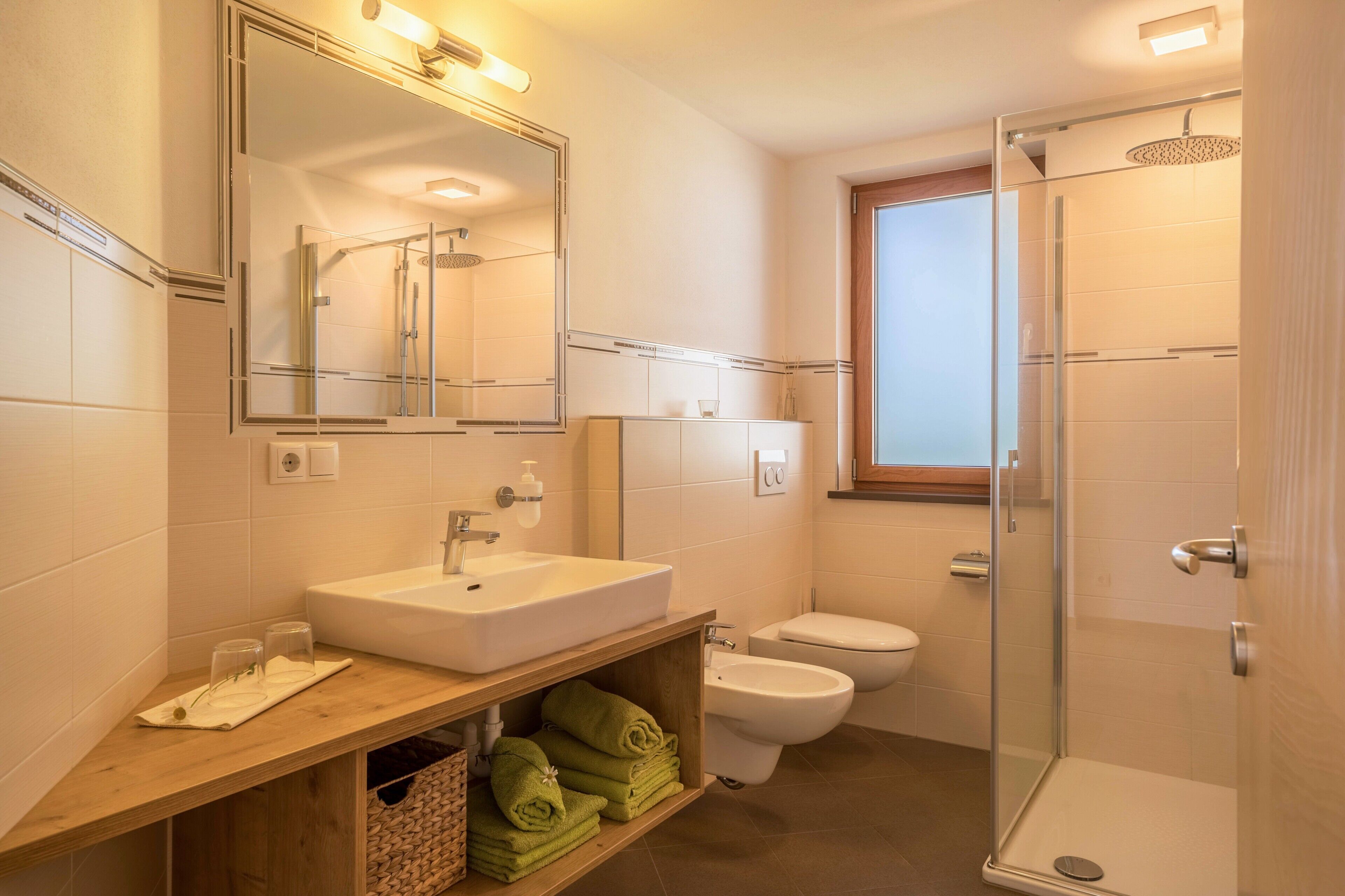 Une salle de bain moderne avec un grand miroir, un lavabo, des toilettes et une douche à parois de verre.
