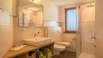 Une salle de bain moderne avec un grand miroir, un lavabo, des toilettes et une douche à parois de verre.