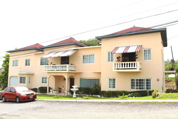 A two-story building with a red car parked in front.