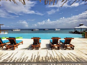 A poolside area with wooden lounge chairs and a view of the ocean.