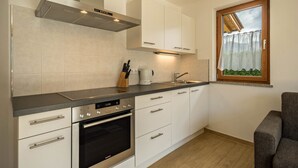 Een moderne keuken met witte kastjes, een roestvrijstalen oven en een raam met uitzicht.