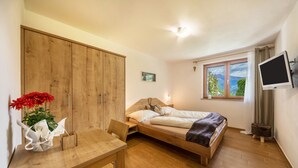 Een slaapkamer met een bed, een bureau, een kledingkast, een televisie en een raam met uitzicht.