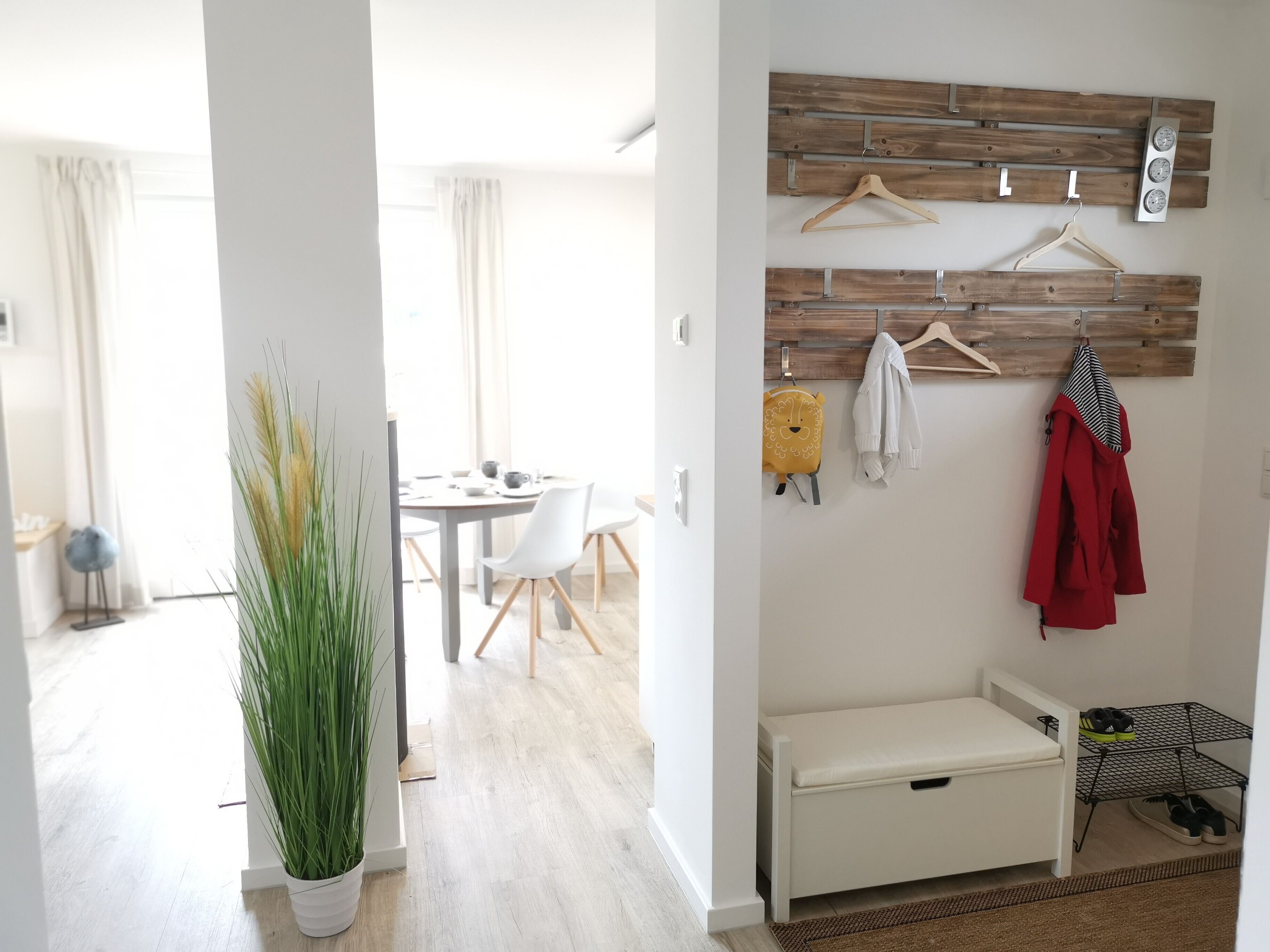 Una habitación moderna con comedor, perchero, banca y zapatero.