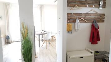 Una habitación moderna con comedor, perchero, banca y zapatero.