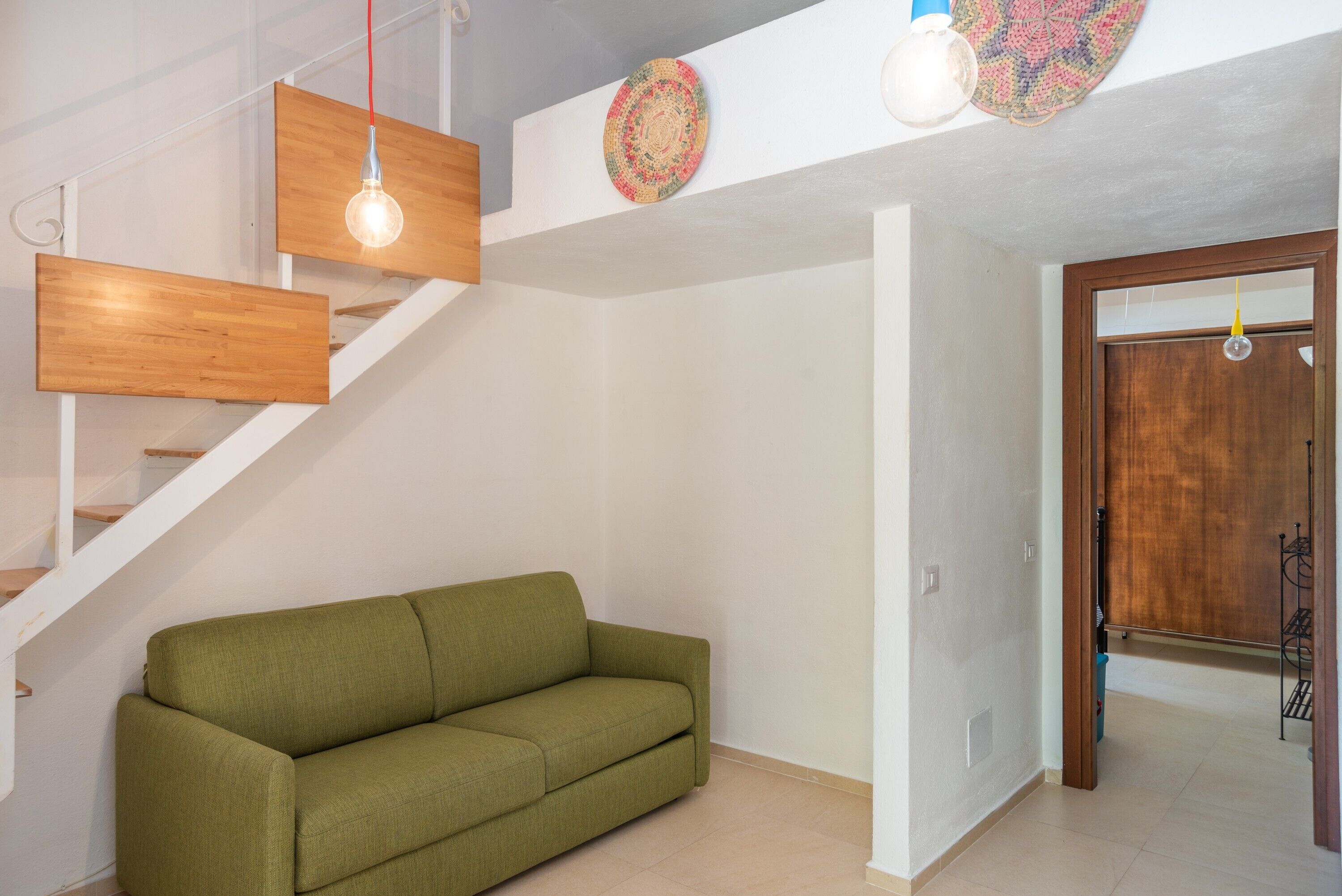 Eine Treppe mit Holzstufen und ein grünes Sofa in einem Raum mit weißen Wänden und einer Holztür.