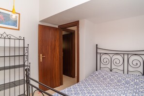 Ein Schlafzimmer mit Bett, Holztür, Metall-Kopfteil und Regaleinheit.